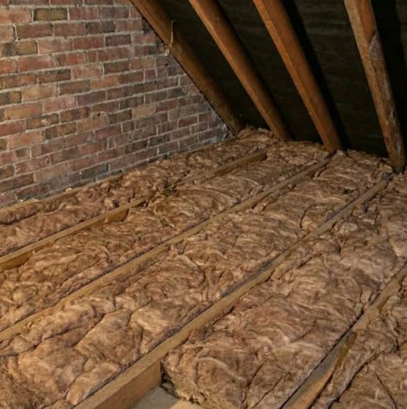 Mineral wool loft insulation fitted between wooden joists in a West Midlands home